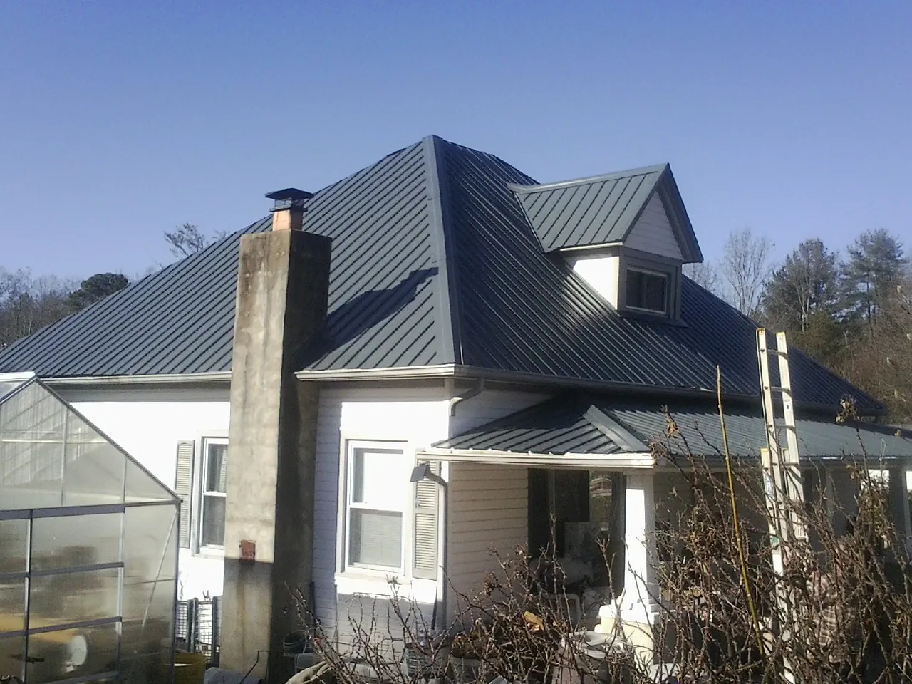 Dark blue standing seam metal roof on a white farmhouse with dormer — Slate & Tile Roof Repair by Roofing Brothers in Fannettsburg