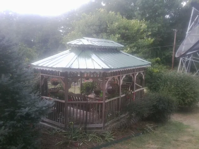 Green metal roof on a backyard gazebo surrounded by garden beds in Fannettsburg
