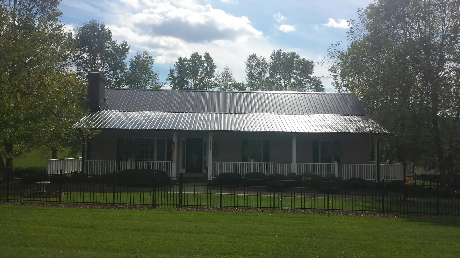 Gray metal roof on a brick ranch with a full width front porch — Gutter Guard Installation work by our crew in Fannettsburg