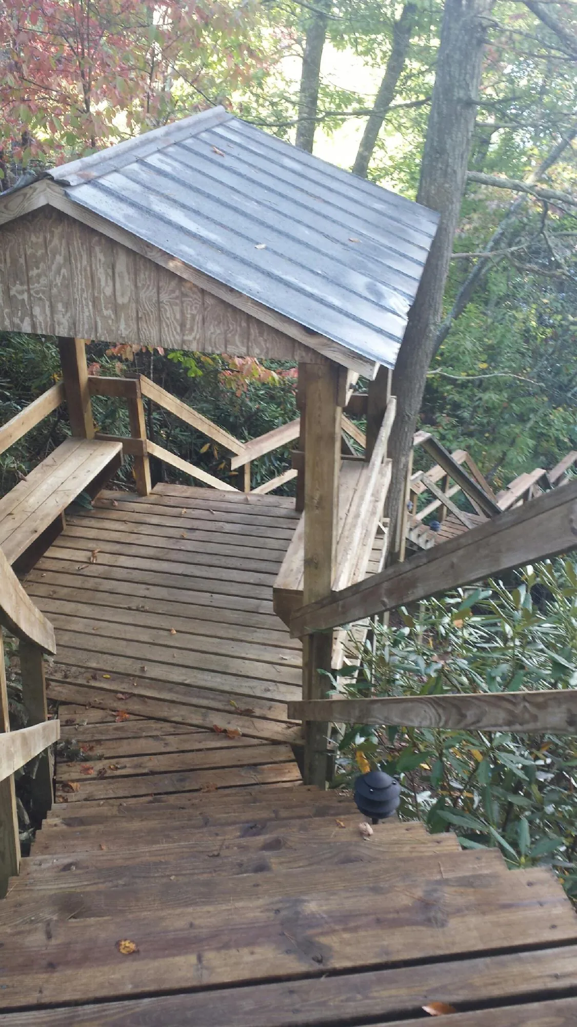 Metal roofed shelter over wooden steps on a wooded walkway — Skylight Repair & Installation work by our crew in Fannettsburg