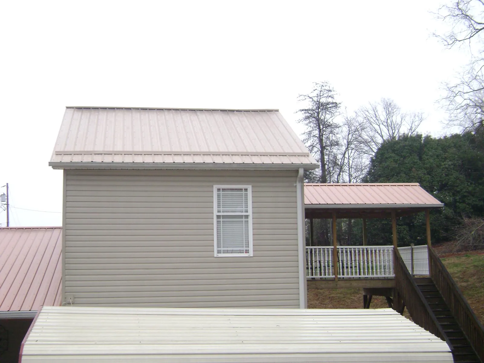 Tan metal roofs on a two story addition and attached porch, from a Roof Replacement job in Fannettsburg