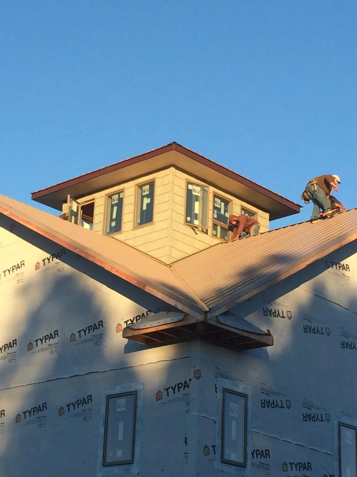 Roofers working around a rooftop cupola on a new metal roof at sunset — Roof Waterproofing in Fannettsburg by Roofing Brothers
